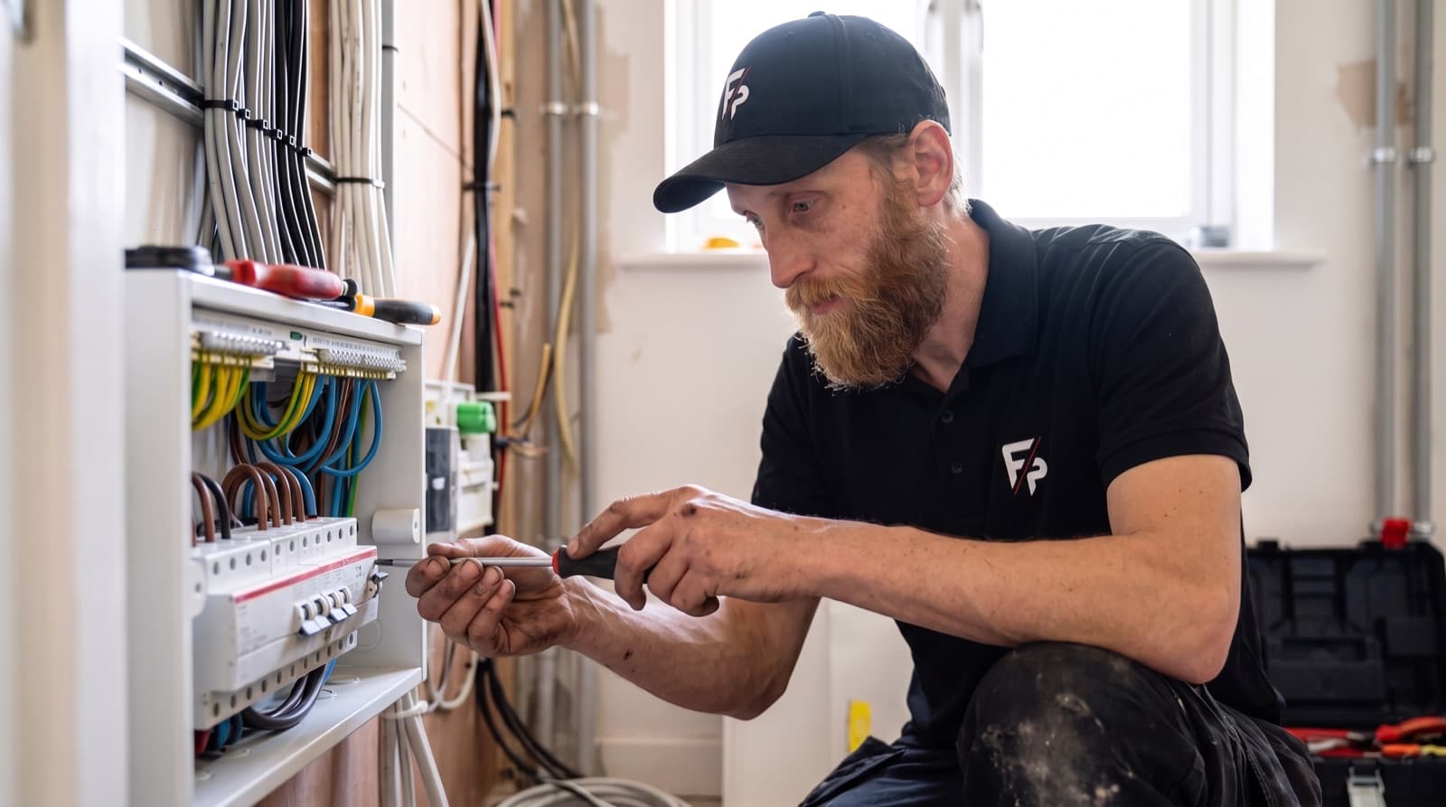 Elektriker verdrahtet einen Sicherungskasten im Rohbau